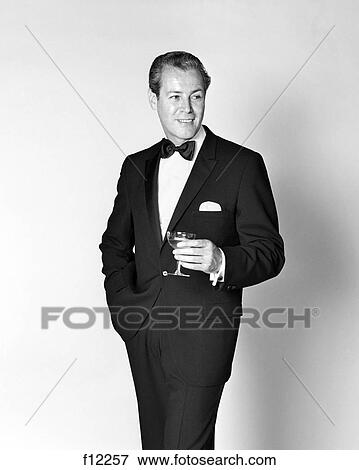 Stock Photo - 1960s SMILING MAN WEARING TUXEDO HOLDING CHAMPAGNE GLASS. Fotosearch