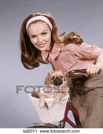1960s SMILING WOMAN LOOKING AT CAMERA LEANING ON HANDLEBARS OF BICYCLE PET PUG DOG IN BASKET View Large Photo Image Stock Image - 1960s SMILING WOMAN LOOKING AT CAMERA LEANING ON HANDLEBARS OF BICYCLE PET PUG DOG IN BASKET. Fotosearch
