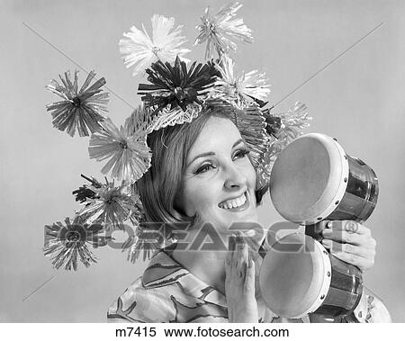 Stock Photography - 1960s SMILING WOMAN WAEARING GOOFY STRAW HAT PLAYING BONGO DRUMS. Fotosearch