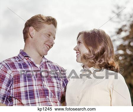 1960s SMILING YOUNG TEENAGE COUPLE LOOKING AT EACH OTHER ROMANTICALLY View Large Photo Image Stock Photography - 1960s SMILING YOUNG TEENAGE COUPLE LOOKING AT EACH OTHER ROMANTICALLY. Fotosearch