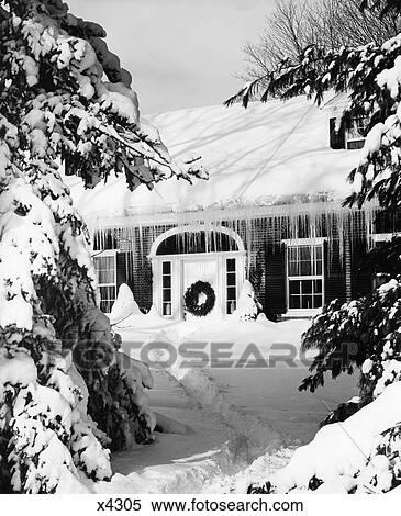 Stock Photography - 1960S Snowed In House In Winter Icicles Hanging From Roof Front Door With Christmas Wreath. Fotosearch
