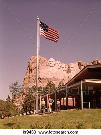 1960s TOURISTS STANDING OUTSIDE INFORMATION CENTER BY AMERICAN FLAG MOUNT RUSHMORE NATIONAL MEMORIAL SOUTH DAKOTA USA View Large Photo Image Stock Image - 1960s TOURISTS STANDING OUTSIDE INFORMATION CENTER BY AMERICAN FLAG MOUNT RUSHMORE NATIONAL MEMORIAL SOUTH DAKOTA USA. Fotosearch
