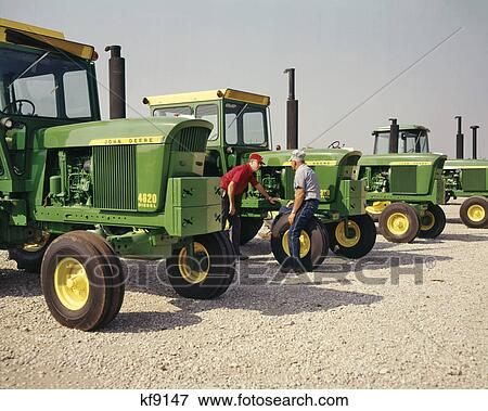 1960s TWO MEN FARMERS INSPECTING DISPLAY OF JOHN DEERE TRACTORS AT FARM EQUIPMENT DEALERSHIP View Large Photo Image Stock Photo - 1960s TWO MEN FARMERS INSPECTING DISPLAY OF JOHN DEERE TRACTORS AT FARM EQUIPMENT DEALERSHIP. Fotosearch