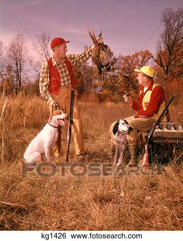 1960s TWO MEN HUNTERS SITTING STANDING WITH HUNTING DOGS HOLDING BRACE OF HARVESTED PHEASANT View Large Photo Image Stock Photograph - 1960s TWO MEN HUNTERS SITTING STANDING WITH HUNTING DOGS HOLDING BRACE OF HARVESTED PHEASANT. Fotosearch