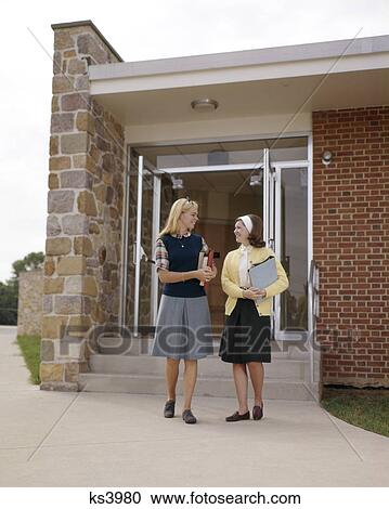 1960s TWO TEEN GIRL STUDENTS TALKING CARRYING BOOKS STANDING FRONT SCHOOL BUILDING View Large Photo Image Stock Image - 1960s TWO TEEN GIRL STUDENTS TALKING CARRYING BOOKS STANDING FRONT SCHOOL BUILDING. Fotosearch