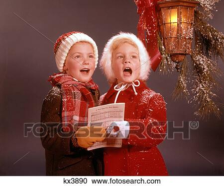 1960s TWO YOUNG CHILDREN BOY AND GIRL WINTER COATS SINGING CAROLS UNDER CHRISTMAS DECORATED CANDLE LANTERN View Large Photo Image Stock Image - 1960s TWO YOUNG CHILDREN BOY AND GIRL WINTER COATS SINGING CAROLS UNDER CHRISTMAS DECORATED CANDLE LANTERN. Fotosearch