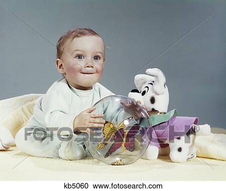 1960s WIDE-EYED BABY CHILD LOOKING AT CAMERA PLAYING WITH TOYS STUFFED ANIMAL AND PLASTIC BALL View Large Photo Image Stock Image - 1960s WIDE-EYED BABY CHILD LOOKING AT CAMERA PLAYING WITH TOYS STUFFED ANIMAL AND PLASTIC BALL. Fotosearch