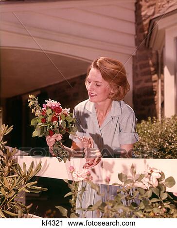 1960s WOMAN HOLDING SMALL BOUQUET OF GARDEN FLOWERS LEANING ON WHITE FENCE View Large Photo Image Stock Image - 1960s WOMAN HOLDING SMALL BOUQUET OF GARDEN FLOWERS LEANING ON WHITE FENCE. Fotosearch