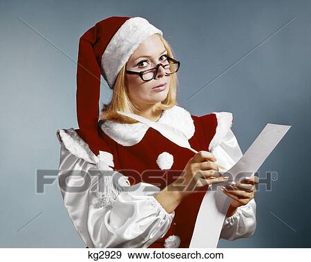 1960s WOMAN IN CHRISTMAS SANTA'S HELPER COSTUME AND CAP WEARING GLASSES LOOKING AT CAMERA CHECKING NAUGHTY OR NICE LIST View Large Photo Image Stock Photo - 1960s WOMAN IN CHRISTMAS SANTA'S HELPER COSTUME AND CAP WEARING GLASSES LOOKING AT CAMERA CHECKING NAUGHTY OR NICE LIST. Fotosearch