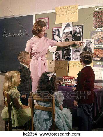 1960s WOMAN SUNDAY SCHOOL TEACHER POINTING AT BULLETIN BOARD WITH TWO BOYS AND TWO GIRLS IN CLASS View Large Photo Image Picture - 1960s WOMAN SUNDAY SCHOOL TEACHER POINTING AT BULLETIN BOARD WITH TWO BOYS AND TWO GIRLS IN CLASS. Fotosearch