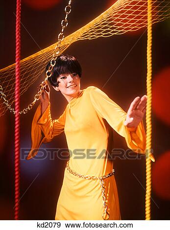 1960s YOUNG WOMAN WEARING YELLOW DRESS CHAIN BELT DISCO DANCING LOOKING AT CAMERA View Large Photo Image Stock Photo - 1960s YOUNG WOMAN WEARING YELLOW DRESS CHAIN BELT DISCO DANCING LOOKING AT CAMERA. Fotosearch