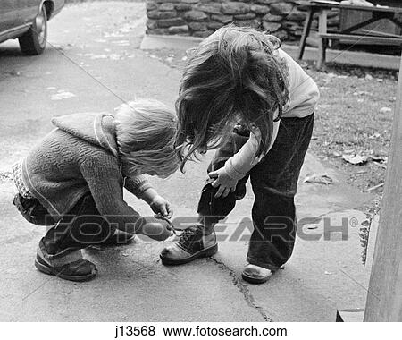 1970s 1970s BLOND BOY BENDING OVER HELPING GIRL TIE HER SHOE View Large Photo Image Stock Photo - 1970s 1970s BLOND BOY BENDING OVER HELPING GIRL TIE HER SHOE. Fotosearch