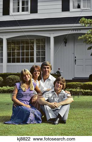1970s 1980s FAMILY SITTING ON LAWN IN FRONT OF SUBURBAN HOME LOOKING AT CAMERA View Large Photo Image Stock Image - 1970s 1980s FAMILY SITTING ON LAWN IN FRONT OF SUBURBAN HOME LOOKING AT CAMERA. Fotosearch