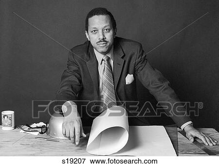 1970S African-American Businessman Contractor Architect Builder At Table With Building Plans And Hard Hat Looking At Camera View Large Photo Image Stock Photo - 1970S African-American Businessman Contractor Architect Builder At Table With Building Plans And Hard Hat Looking At Camera. Fotosearch
