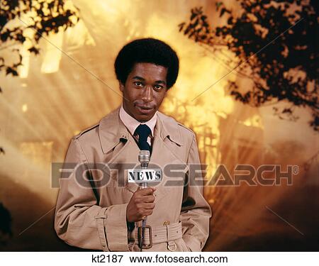 1970s AFRICAN AMERICAN MAN TELEVISION NEWS REPORTER WEARING RAINCOAT SPEAKING INTO MICROPHONE AT FIRE SCENE LOOKING AT CAMERA View Large Photo Image Stock Photo - 1970s AFRICAN AMERICAN MAN TELEVISION NEWS REPORTER WEARING RAINCOAT SPEAKING INTO MICROPHONE AT FIRE SCENE LOOKING AT CAMERA. Fotosearch