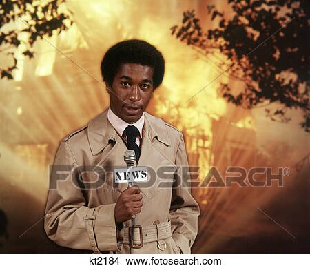 Picture - 1970s AFRICAN AMERICAN MAN TV REPORTER AT SCENE OF FIRE SPEAKING TO MICROPHONE LOOKING AT CAMERA. Fotosearch