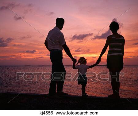 1970s ANONYMOUS SILHOUETTED FAMILY OF THREE MOTHER FATHER DAUGHTER BACKLIT AT BEACH WATCHING SUNSET View Large Photo Image Stock Photograph - 1970s ANONYMOUS SILHOUETTED FAMILY OF THREE MOTHER FATHER DAUGHTER BACKLIT AT BEACH WATCHING SUNSET. Fotosearch