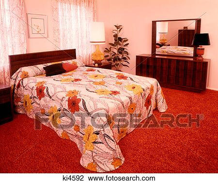 Stock Image - 1970s BEDROOM BED FLORAL QUILT BLANKET RED RUG CARPET DAYLIGHT. Fotosearch