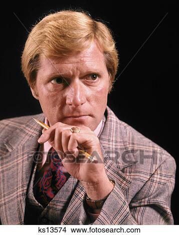 1970s BLOND BUSINESSMAN WITH AMBIGUOUS FACIAL EXPRESSION WEARING THREE PIECE PLAID SUIT HOLDING PENCIL View Large Photo Image Picture - 1970s BLOND BUSINESSMAN WITH AMBIGUOUS FACIAL EXPRESSION WEARING THREE PIECE PLAID SUIT HOLDING PENCIL. Fotosearch