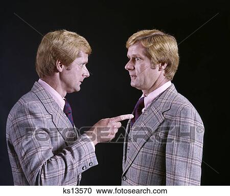 Stock Image - 1970s BLOND MAN IN PLAID THREE PIECE SUIT POINTING ACCUSING FINGER AT HIMSELF HUMOROUS DOUBLE EXPOSURE. Fotosearch