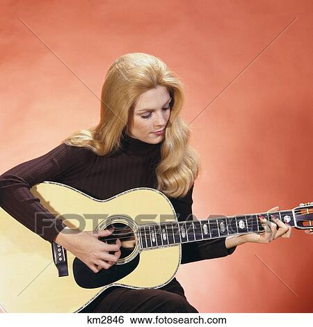 Stock Photograph - 1970s BLOND WOMAN PLAYING GUITAR. Fotosearch