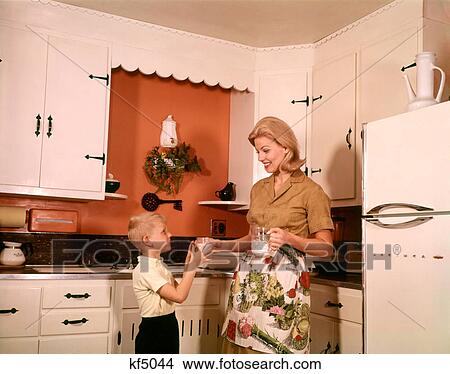 1970s BLONDE MOTHER GIVING SON GLASS MILK IN KITCHEN View Large Photo Image Picture - 1970s BLONDE MOTHER GIVING SON GLASS MILK IN KITCHEN. Fotosearch