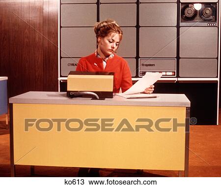 1970s BORED EXPRESSIONLESS WOMAN READING PAPERS SITTING AT YELLOW DESK DATA ENTRY INTO COMPUTER SYSTEM R1 SYSTEM View Large Photo Image Stock Image - 1970s BORED EXPRESSIONLESS WOMAN READING PAPERS SITTING AT YELLOW DESK DATA ENTRY INTO COMPUTER SYSTEM R1 SYSTEM. Fotosearch