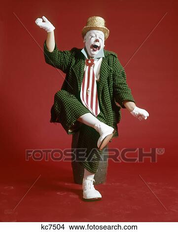 1970s CLOWN GREEN CHECKED BAGGY SUIT SILLY EXPRESSION SITTING ON BARREL LIFTING LEG ARMS IN AIR YAWNING View Large Photo Image Picture - 1970s CLOWN GREEN CHECKED BAGGY SUIT SILLY EXPRESSION SITTING ON BARREL LIFTING LEG ARMS IN AIR YAWNING. Fotosearch