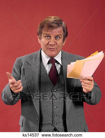 1970s CONCERNED BUSINESSMAN HOLDING PAPERS GESTURING AND LOOKING AT CAMERA View Large Photo Image Stock Photo - 1970s CONCERNED BUSINESSMAN HOLDING PAPERS GESTURING AND LOOKING AT CAMERA. Fotosearch