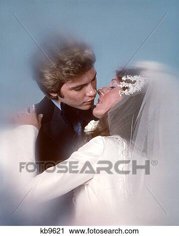 Stock Image - 1970S Couple Bride Groom Wedding Kiss Embracing. Fotosearch
