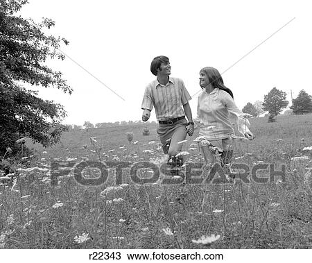 1970s COUPLE HOLDING HANDS WALKING IN HIGH FIELD WITH QUEEN ANNE'S LACE View Large Photo Image Stock Image - 1970s COUPLE HOLDING HANDS WALKING IN HIGH FIELD WITH QUEEN ANNE'S LACE. Fotosearch