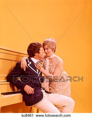 1970s COUPLE MAN WOMAN WEARING 1920s CLOTHES LEANING ON YELLOW UPRIGHT PIANO View Large Photo Image Stock Image - 1970s COUPLE MAN WOMAN WEARING 1920s CLOTHES LEANING ON YELLOW UPRIGHT PIANO. Fotosearch