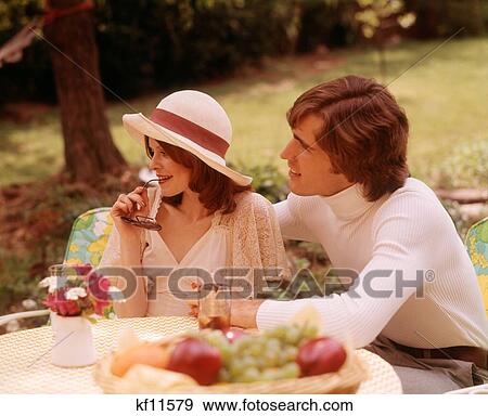 Stock Photo - 1970S Couple Sitting Table Eating Drinking Looking Off To The Side. Fotosearch