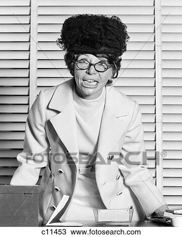1970s CRAZY BUSINESSWOMAN AT OFFICE DESK WEARING HAT EYEGLASSES DISHEVELED ANGRY FACIAL EXPRESSION LOOKING AT CAMERA View Large Photo Image Stock Image - 1970s CRAZY BUSINESSWOMAN AT OFFICE DESK WEARING HAT EYEGLASSES DISHEVELED ANGRY FACIAL EXPRESSION LOOKING AT CAMERA. Fotosearch