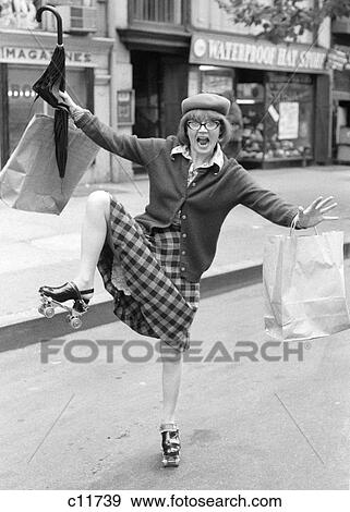 1970s CRAZY WILDLY GESTURING SHOPPING BAG LADY WOMAN ON ROLLER SKATES ON CITY STREET LOOKING AT CAMERA View Large Photo Image Stock Photo - 1970s CRAZY WILDLY GESTURING SHOPPING BAG LADY WOMAN ON ROLLER SKATES ON CITY STREET LOOKING AT CAMERA. Fotosearch