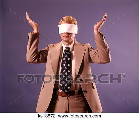 1970s EXECUTIVE MAN WEARING BUSINESS SUIT WEARING BLINDFOLD HOLDING BOTH HANDS UP IN HOPELESS GESTURE View Large Photo Image Stock Image - 1970s EXECUTIVE MAN WEARING BUSINESS SUIT WEARING BLINDFOLD HOLDING BOTH HANDS UP IN HOPELESS GESTURE. Fotosearch