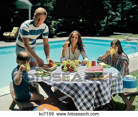 1970s FAMILY BACKYARD SWIMMING POOL EATING FRESH FRUIT PICNIC MAN WOMAN BOY GIRL LOOKING AT CAMERA View Large Photo Image Stock Photo - 1970s FAMILY BACKYARD SWIMMING POOL EATING FRESH FRUIT PICNIC MAN WOMAN BOY GIRL LOOKING AT CAMERA. Fotosearch