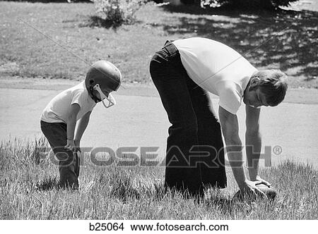 1970s FATHER PLAYING FOOTBALL ON GRASS IN WITH YOUNG SON View Large Photo Image Picture - 1970s FATHER PLAYING FOOTBALL ON GRASS IN WITH YOUNG SON. Fotosearch