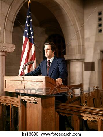 1970s MAN STANDING SPEAKING AT PODIUM BESIDE AN AMERICAN FLAG View Large Photo Image Stock Image - 1970s MAN STANDING SPEAKING AT PODIUM BESIDE AN AMERICAN FLAG. Fotosearch