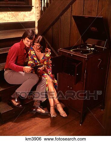 1970S Man Woman Romantic Couple Playing 78 Rpm Records On Antique Windup Victrola Phonograph View Large Photo Image Stock Photograph - 1970S Man Woman Romantic Couple Playing 78 Rpm Records On Antique Windup Victrola Phonograph. Fotosearch