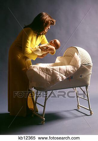 1970s MOTHER WEARING YELLOW ROBE PUTTING BABY CHILD TO SLEEP IN WHITE WOVEN WICKER BASSINET View Large Photo Image Stock Photography - 1970s MOTHER WEARING YELLOW ROBE PUTTING BABY CHILD TO SLEEP IN WHITE WOVEN WICKER BASSINET. Fotosearch