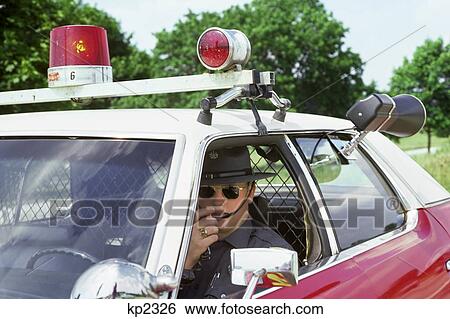 1970s POLICE OFFICER LOOKING AT CAMERA SITTING PATROL CAR TALKING ON RADIO RADAR GUN MOUNTED CHECKING FOR SPEEDING VIOLATIONS View Large Photo Image Stock Photograph - 1970s POLICE OFFICER LOOKING AT CAMERA SITTING PATROL CAR TALKING ON RADIO RADAR GUN MOUNTED CHECKING FOR SPEEDING VIOLATIONS. Fotosearch