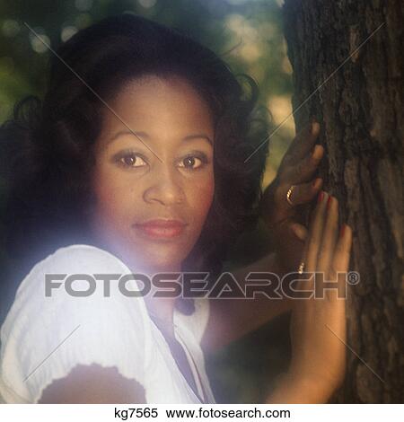 1970s PORTRAIT AFRICAN AMERICAN WOMAN OUTDOORS BY TREE LOOKING AT CAMERA View Large Photo Image Stock Photography - 1970s PORTRAIT AFRICAN AMERICAN WOMAN OUTDOORS BY TREE LOOKING AT CAMERA. Fotosearch