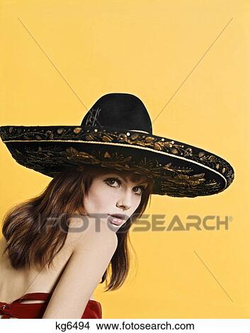 Picture - 1970'S Portrait Attractive Sultry Brunette Woman Wearing Gold Embroidered Black Mexican Sombrero Looking At Camera Over Shoulder. Fotosearch