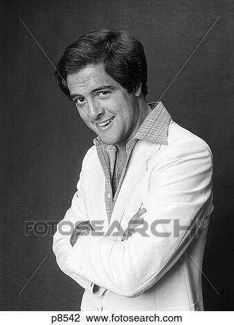 Stock Image - 1970S Portrait Of Man In White Sports Jacket Looking At Camera With Sly Smile . Fotosearch