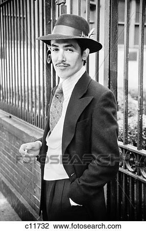 1970S Portrait Slick Young Latino Hispanic Man Wearing Hat Vest And Suite Smoking Cigarette Looking At Camera View Large Photo Image Stock Image - 1970S Portrait Slick Young Latino Hispanic Man Wearing Hat Vest And Suite Smoking Cigarette Looking At Camera. Fotosearch
