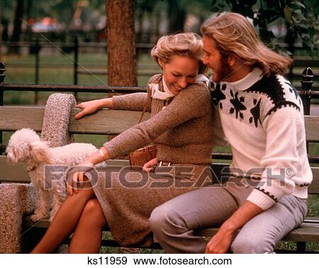 1970s ROMANTIC COUPLE PARK BENCH WITH WHITE DOG MAN HAS BEARD LONG HAIR WOMAN FLIRTING LOVE ROMANCE View Large Photo Image Stock Photo - 1970s ROMANTIC COUPLE PARK BENCH WITH WHITE DOG MAN HAS BEARD LONG HAIR WOMAN FLIRTING LOVE ROMANCE. Fotosearch