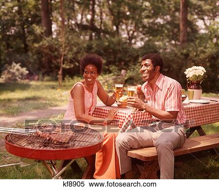 1970S Smiling African American Couple Man Woman Drinking Beer At Backyard Barbecue View Large Photo Image Stock Photography - 1970S Smiling African American Couple Man Woman Drinking Beer At Backyard Barbecue. Fotosearch