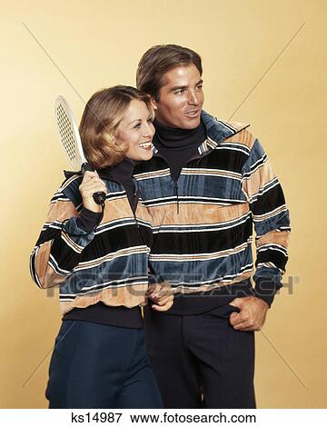 1970s SMILING COUPLE MAN WOMAN HOLDING SQUASH RACKET WEARING MATCHING STRIPED VELOUR PULLOVER SWEATERS FASHION SPORTSWEAR View Large Photo Image Stock Photo - 1970s SMILING COUPLE MAN WOMAN HOLDING SQUASH RACKET WEARING MATCHING STRIPED VELOUR PULLOVER SWEATERS FASHION SPORTSWEAR. Fotosearch