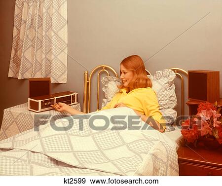 1970s SMILING REDHEADED WOMAN LYING IN BED SETTING ALARM CLOCK RADIO TO WAKE UP IN THE MORNING View Large Photo Image Stock Photo - 1970s SMILING REDHEADED WOMAN LYING IN BED SETTING ALARM CLOCK RADIO TO WAKE UP IN THE MORNING. Fotosearch